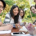 young-students-sitting-studying-outdoors-while-talking